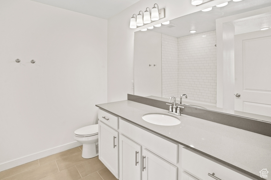 Bathroom with tile patterned flooring, baseboards, vanity, toilet, and a shower