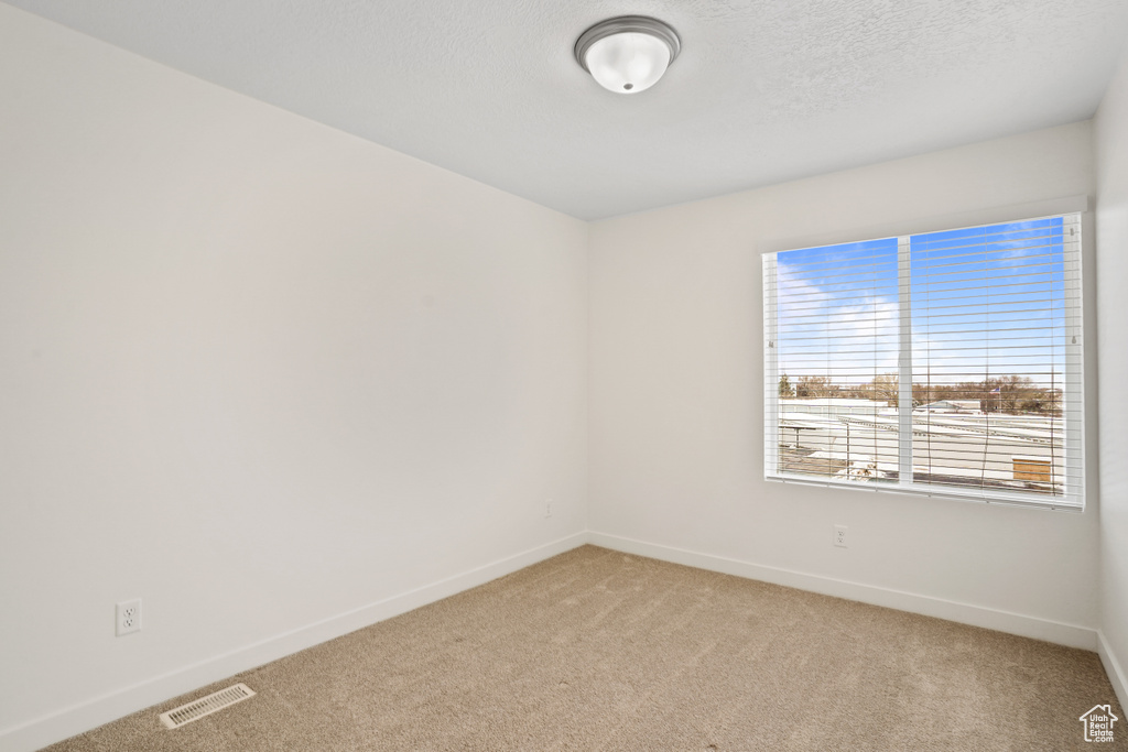 Empty room featuring light colored carpet and baseboards