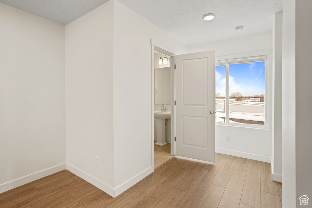 Spare room featuring light wood-type flooring, baseboards, and a smoke detector