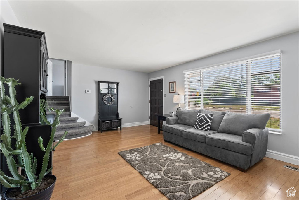 Living room featuring baseboards, wood finished floors, and stairway
