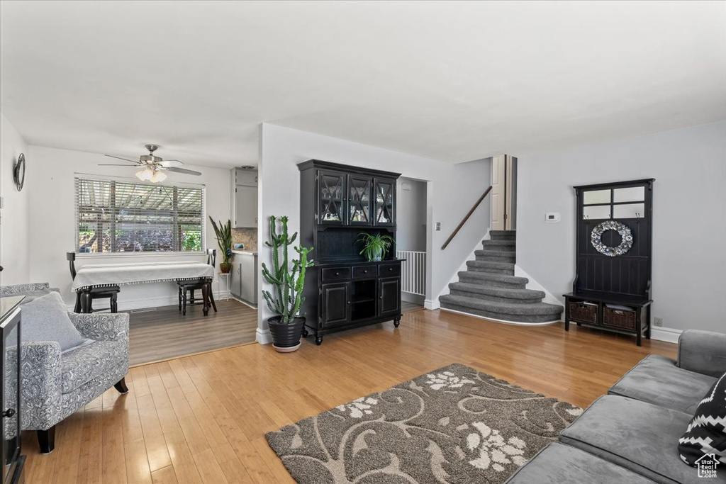Living area featuring a ceiling fan, light wood-style floors, stairs, and radiator heating unit