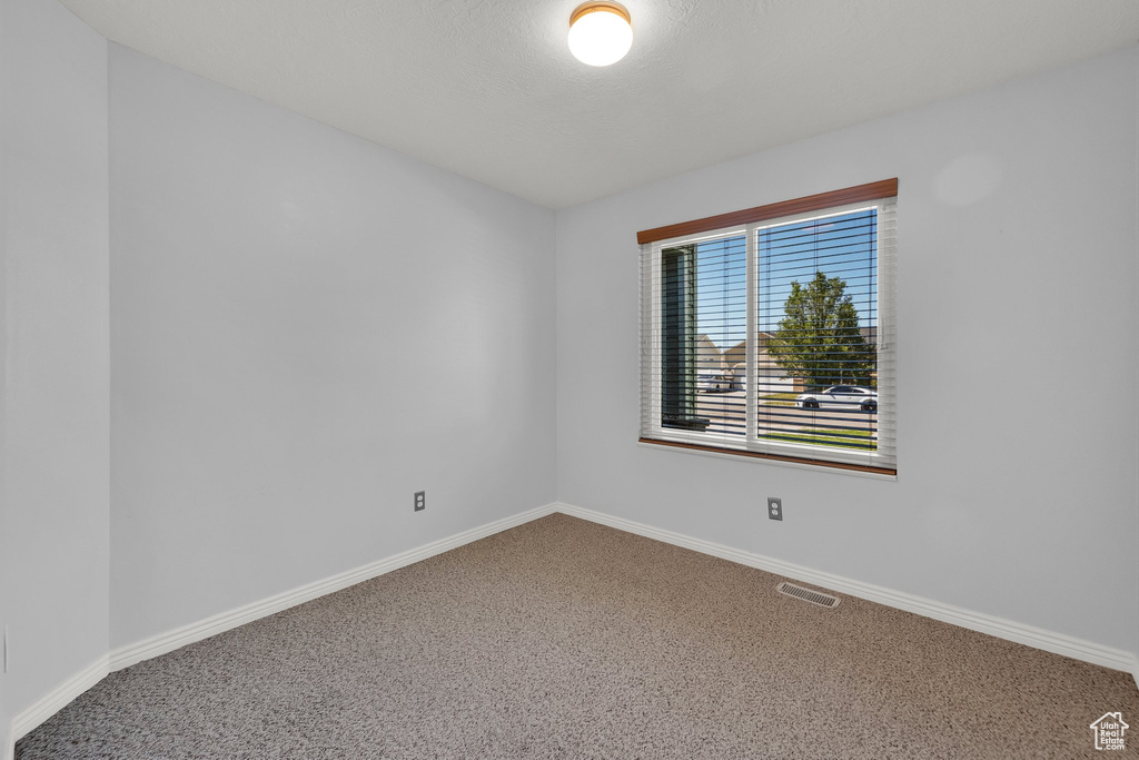 Carpeted spare room featuring baseboards