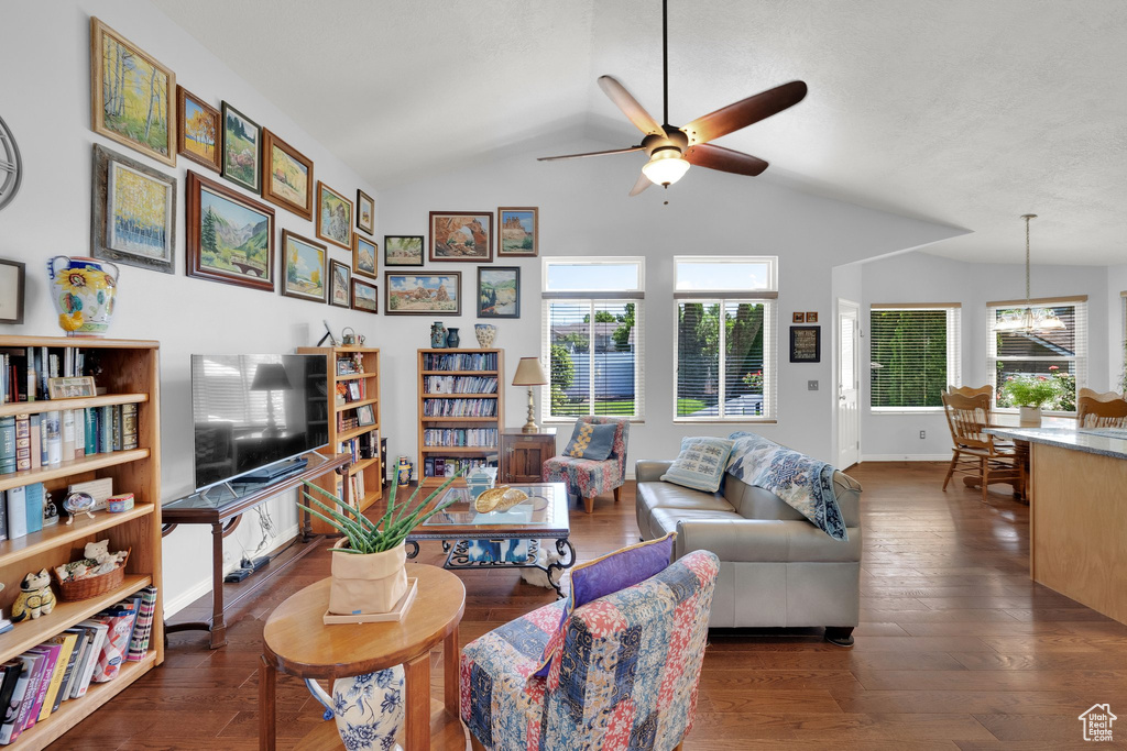 Living room with ceiling fan, vaulted ceiling, plenty of natural light, wood finished floors, and a chandelier