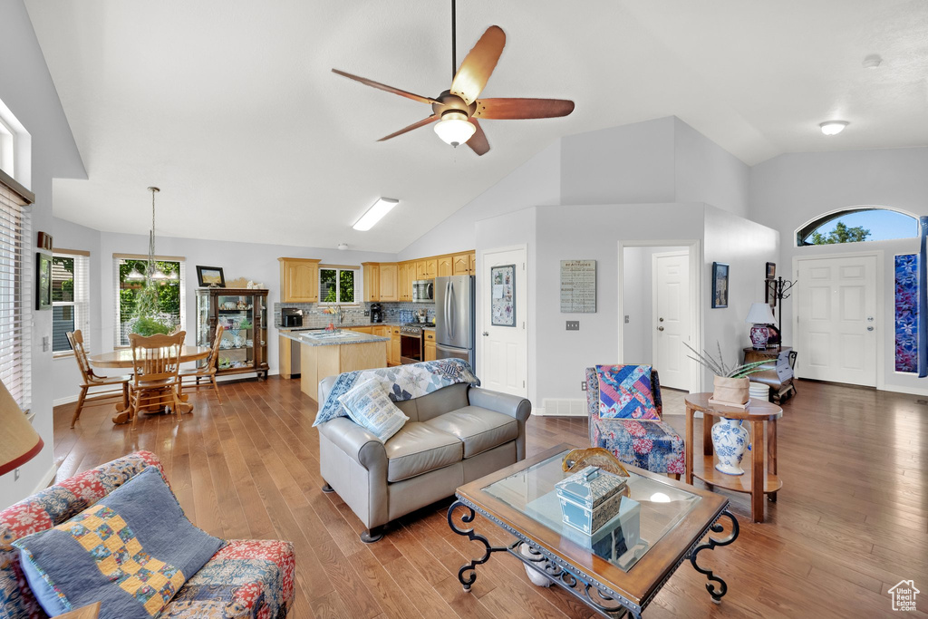 Living room with light wood-type flooring, a ceiling fan, and high vaulted ceiling