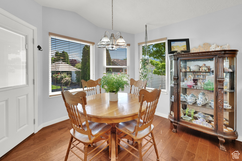 Dining area featuring a chandelier, hardwood / wood-style floors, and vaulted ceiling