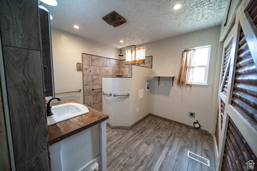 Full bath featuring vanity, wood finished floors, a textured ceiling, and recessed lighting