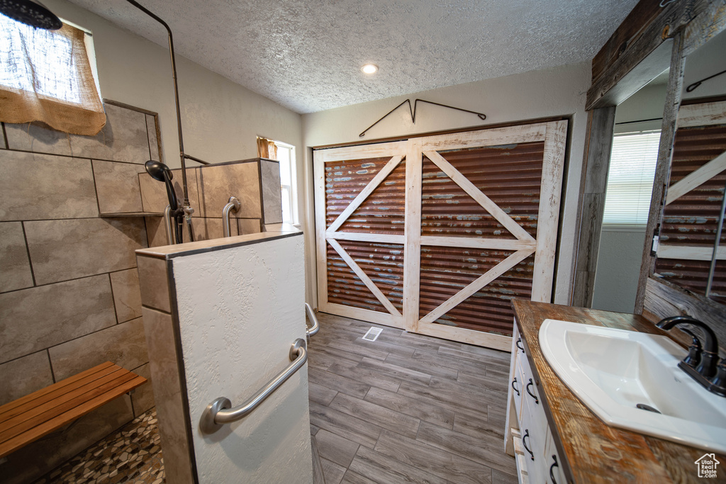 Bathroom featuring a textured ceiling, a walk in shower, and vanity
