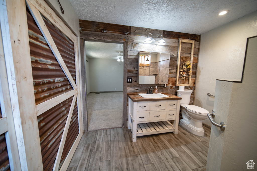 Bathroom featuring a textured ceiling, vanity, wood finished floors, and ceiling fan