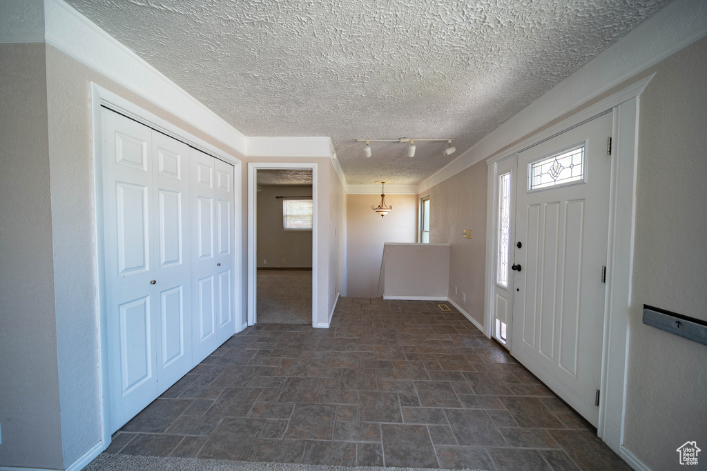 Foyer with stone finish floors, track lighting, and a textured ceiling