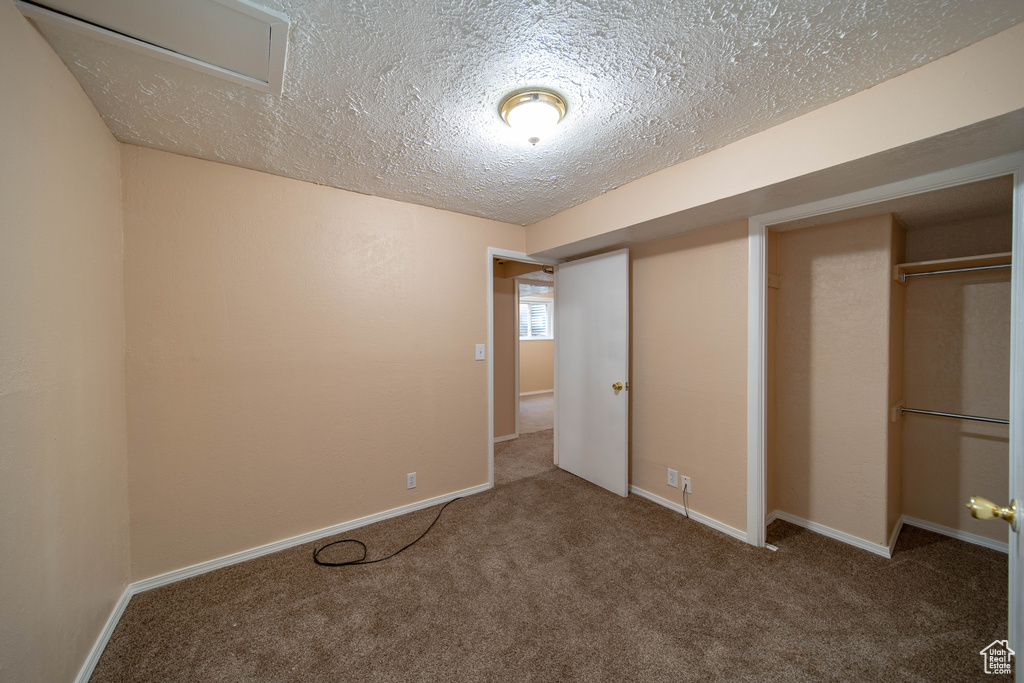 Unfurnished bedroom featuring a textured ceiling, carpet floors, and a closet