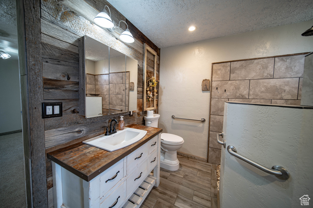Bathroom featuring a textured ceiling, vanity, tasteful backsplash, wood finished floors, and recessed lighting