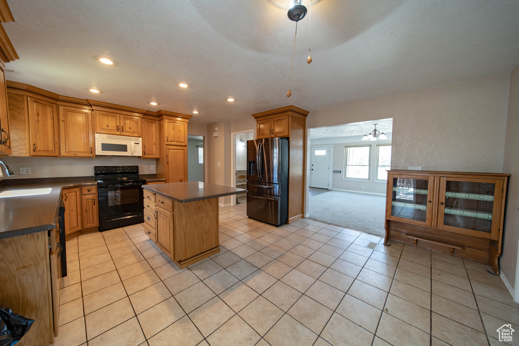 Kitchen featuring black electric range oven, white microwave, stainless steel fridge with ice dispenser, dark countertops, and a center island