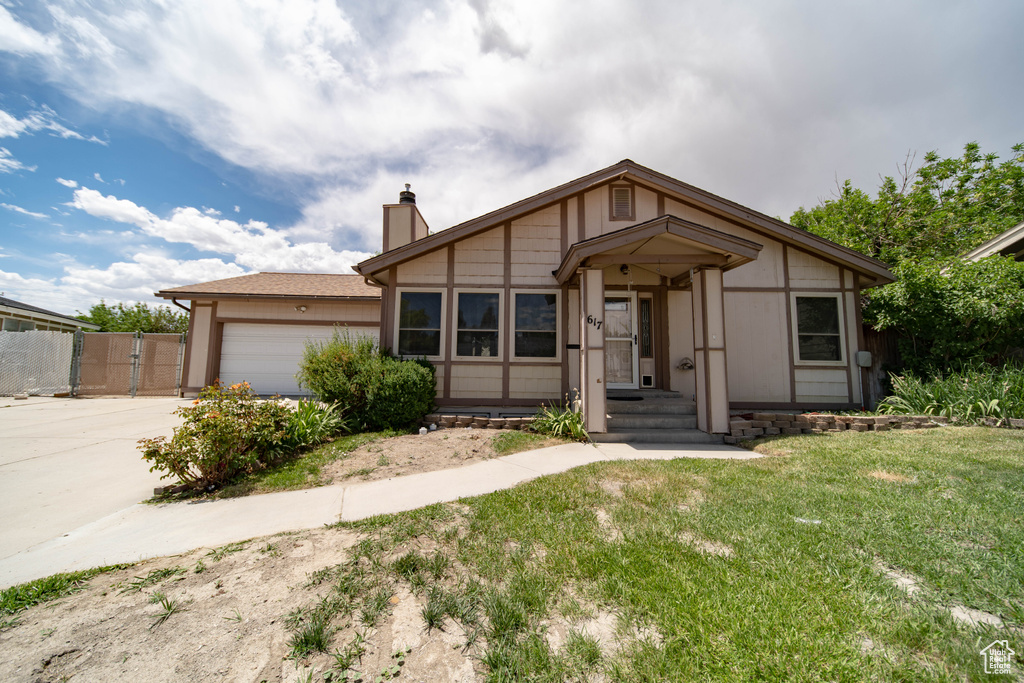 View of front of home featuring a chimney, driveway, an attached garage, and a gate