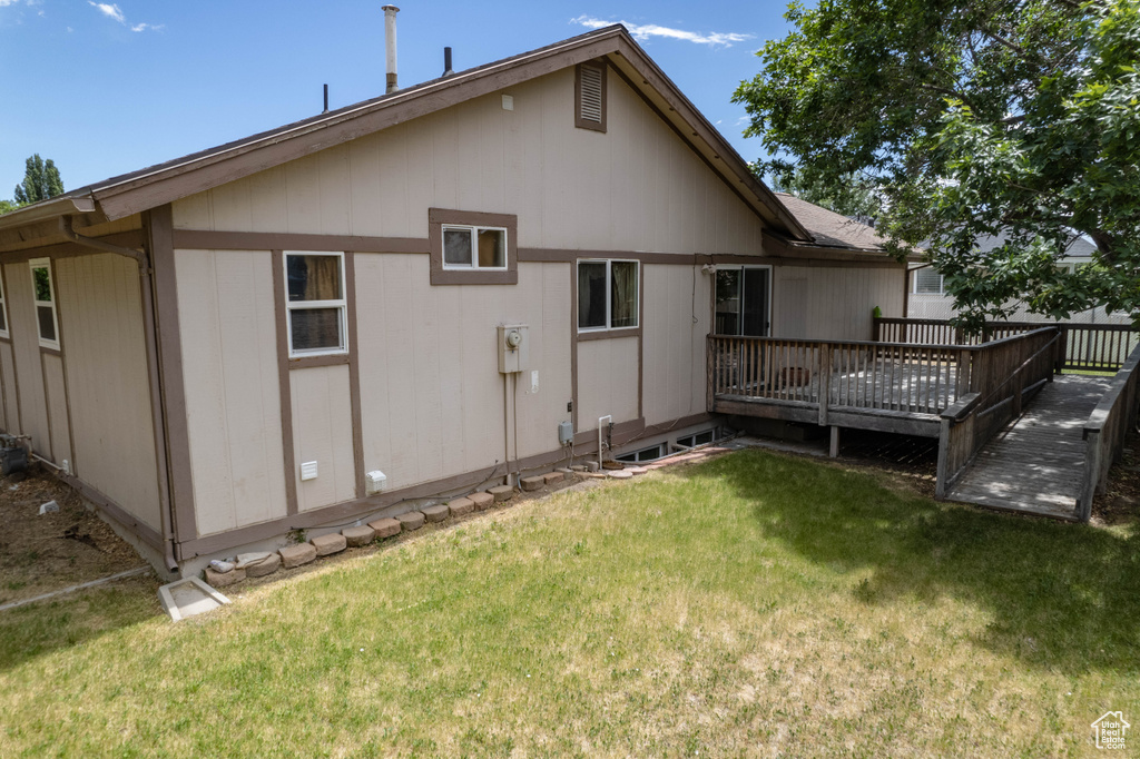 Rear view of property featuring a deck and a lawn