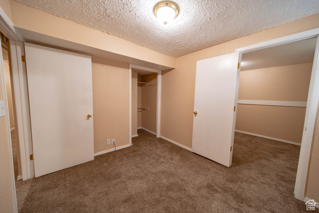 Unfurnished bedroom featuring a textured ceiling, carpet, and a closet