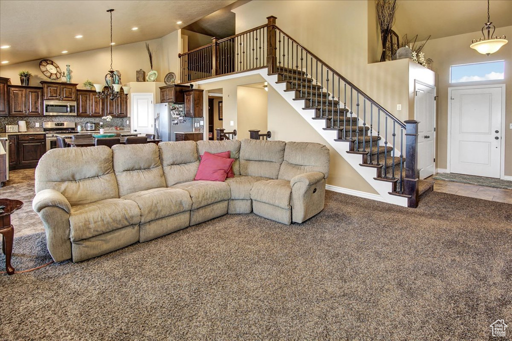 Living room with high vaulted ceiling, stairway, carpet, baseboards, and recessed lighting