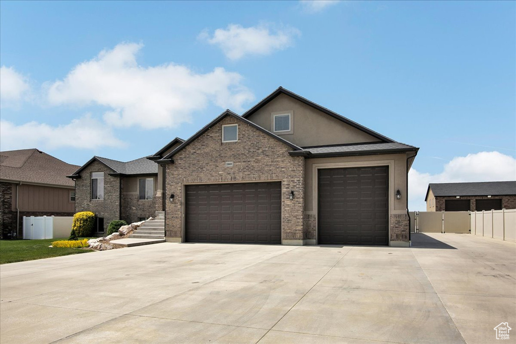 View of front of house with concrete driveway, a garage, stucco siding, and brick siding