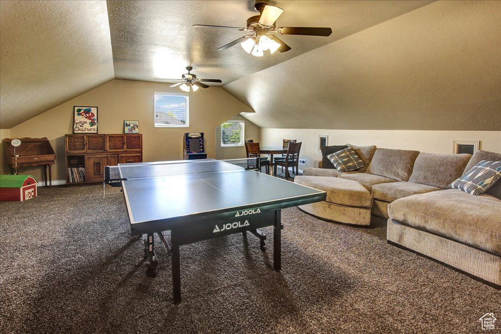 Rec room with carpet flooring, vaulted ceiling, a ceiling fan, and a textured ceiling