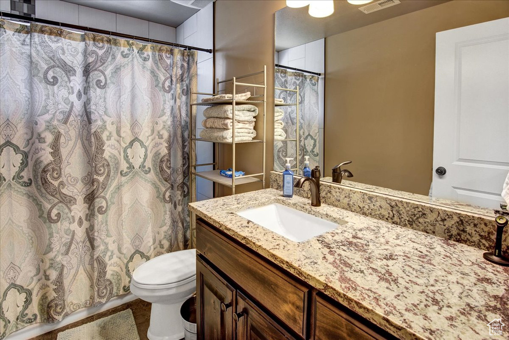 Bathroom featuring vanity, toilet, and curtained shower
