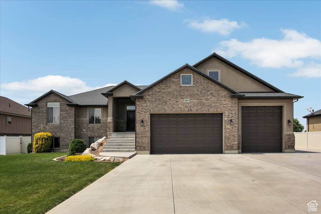 View of front of property featuring a garage, concrete driveway, brick siding, and stucco siding