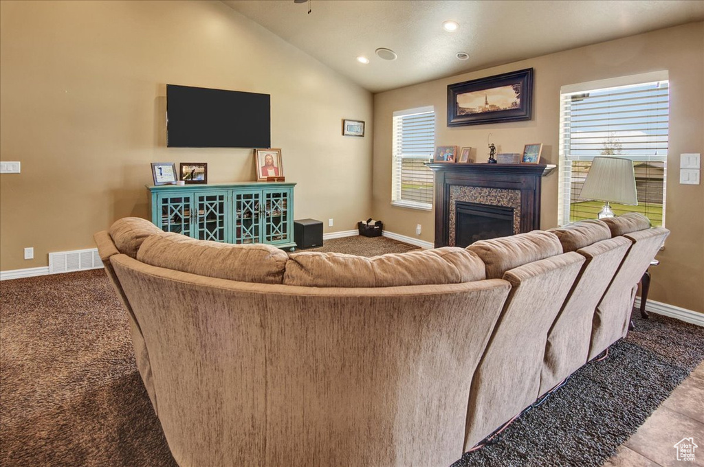 Living area featuring baseboards, a glass covered fireplace, lofted ceiling, carpet, and recessed lighting