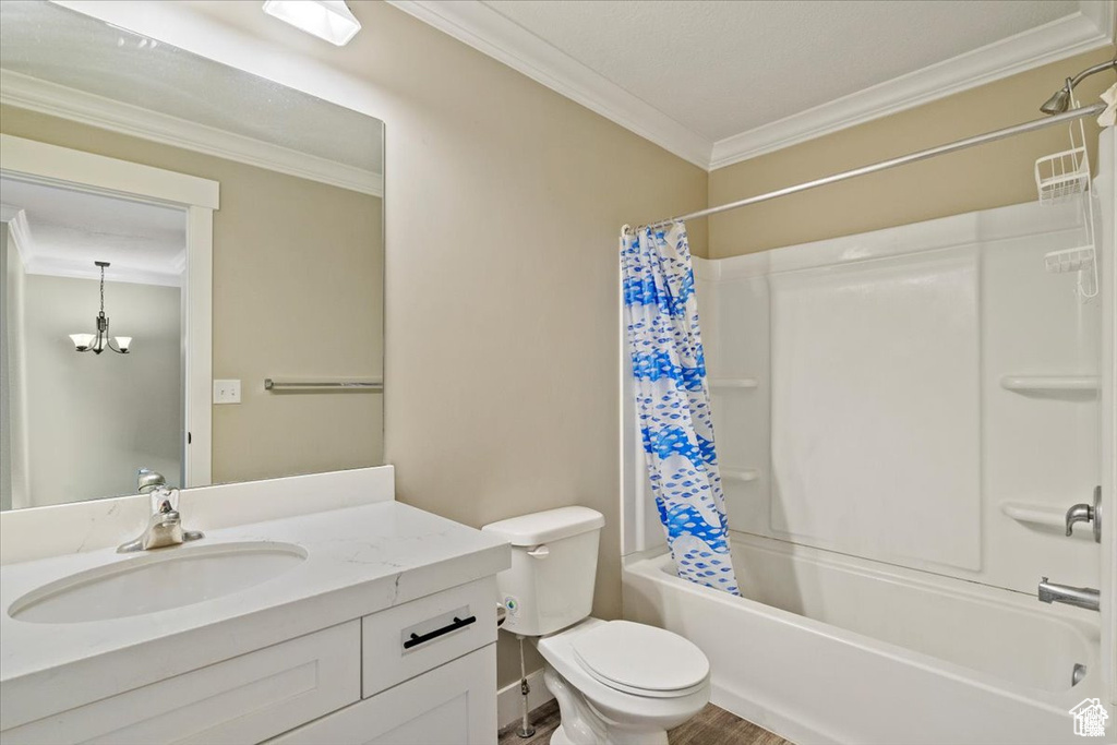 Bathroom featuring vanity, ornamental molding, shower / tub combo, toilet, and a chandelier