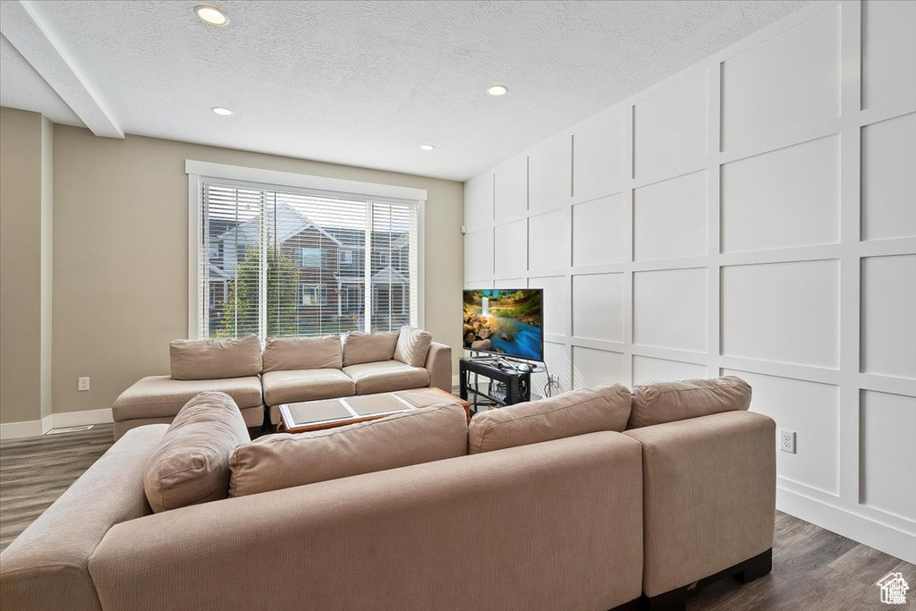 Living room with dark wood-style floors, baseboards, recessed lighting, and a textured ceiling