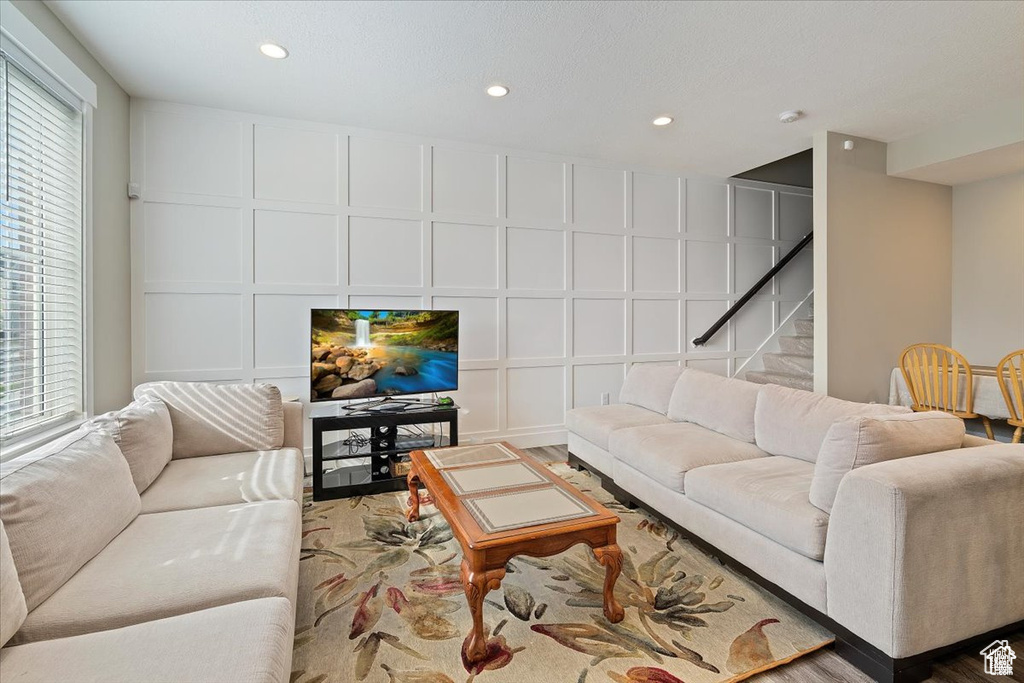 Living room featuring a decorative wall, stairs, recessed lighting, and wood finished floors