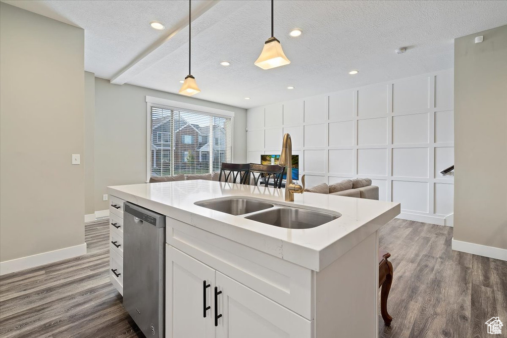 Kitchen featuring dishwasher, a sink, decorative light fixtures, dark wood-style flooring, and baseboards