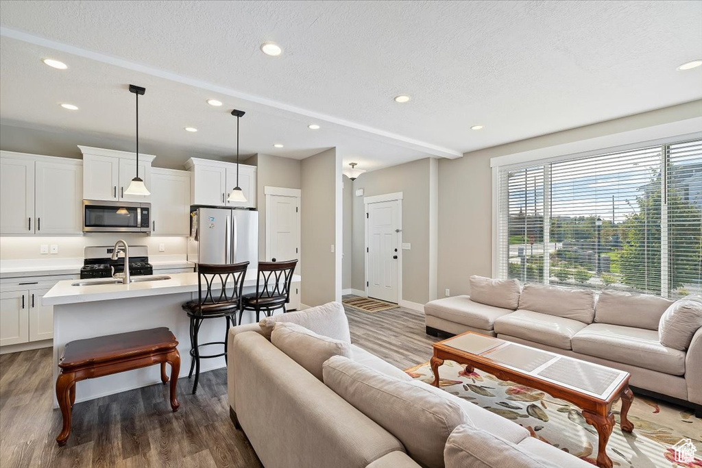 Living area featuring recessed lighting, wood finished floors, a textured ceiling, and baseboards