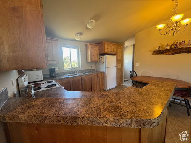 Kitchen with white appliances, brown cabinets, a chandelier, a peninsula, and hanging light fixtures