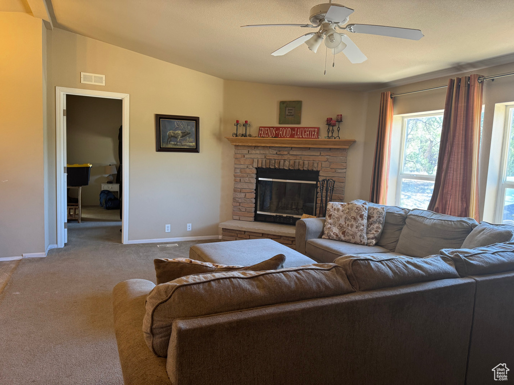 Carpeted living area with a ceiling fan, a fireplace, and vaulted ceiling