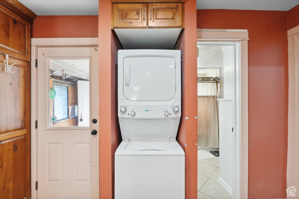 Laundry room featuring stacked washer / drying machine and light tile patterned flooring