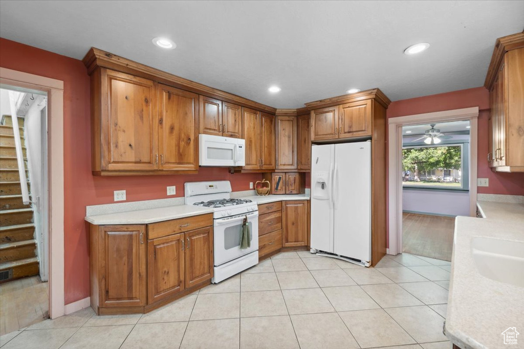Kitchen featuring white appliances, light countertops, brown cabinets, and recessed lighting