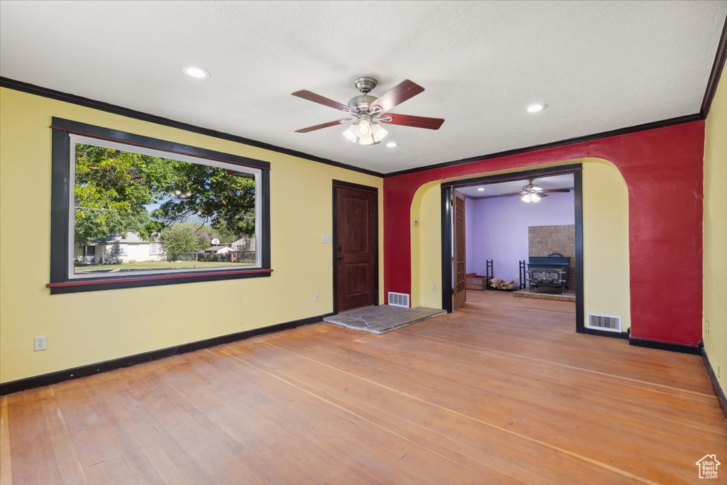 Spare room with arched walkways, a ceiling fan, crown molding, light wood finished floors, and recessed lighting