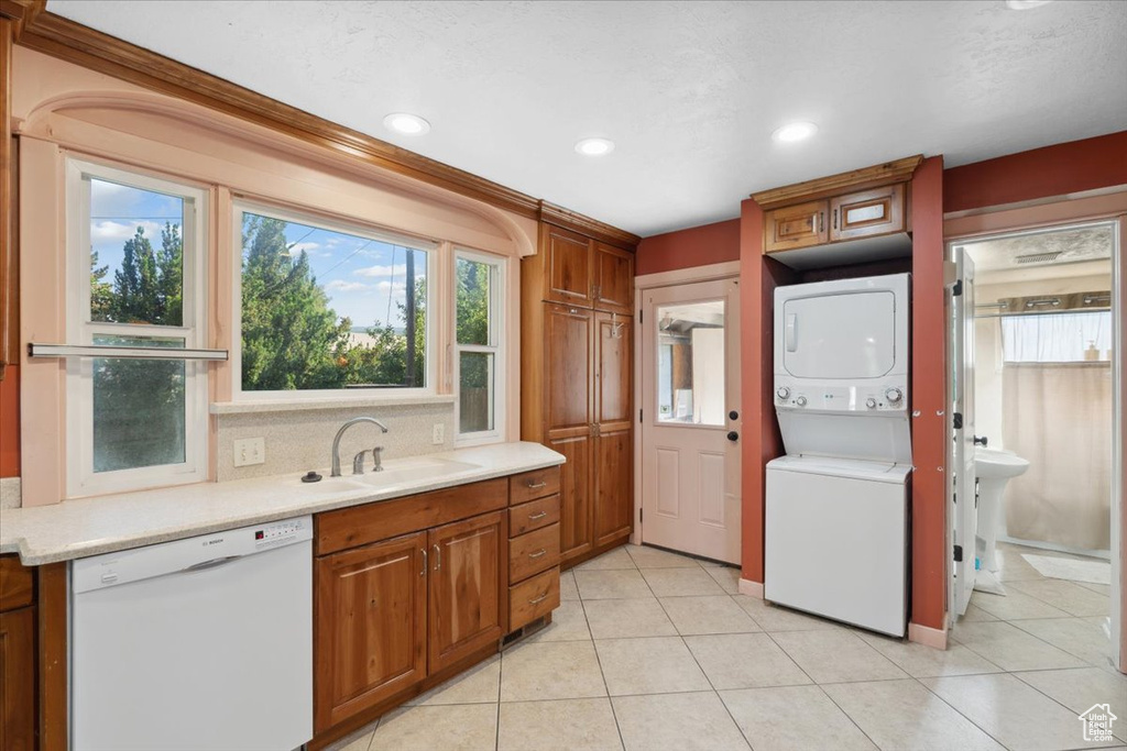 Kitchen with dishwasher, stacked washer / drying machine, light countertops, brown cabinets, and recessed lighting