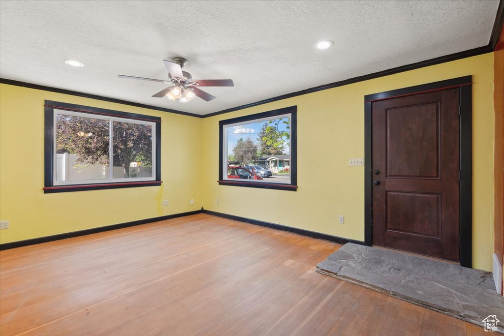 Entrance foyer featuring ornamental molding, wood finished floors, a textured ceiling, plenty of natural light, and a ceiling fan