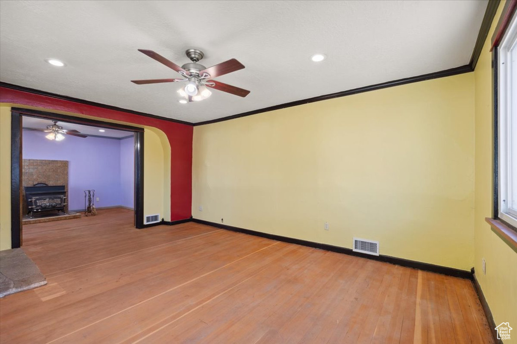 Empty room with ceiling fan, light wood finished floors, crown molding, recessed lighting, and arched walkways