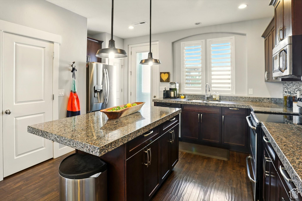 Kitchen with appliances with stainless steel finishes, a sink, dark wood-style flooring, recessed lighting, and dark brown cabinets