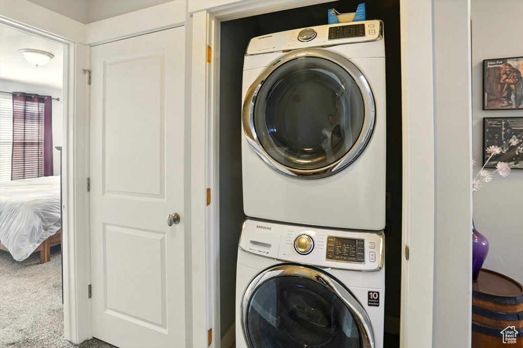 Laundry area with estacked washer and dryer and carpet floors
