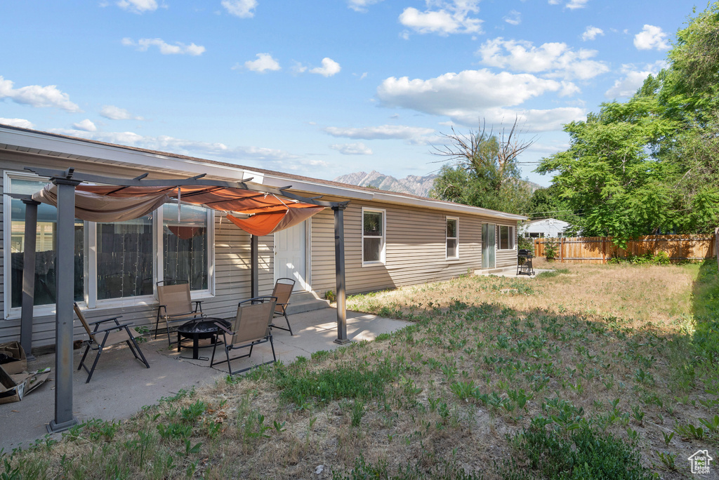 Back of house with a fire pit, a patio area, and a mountain view