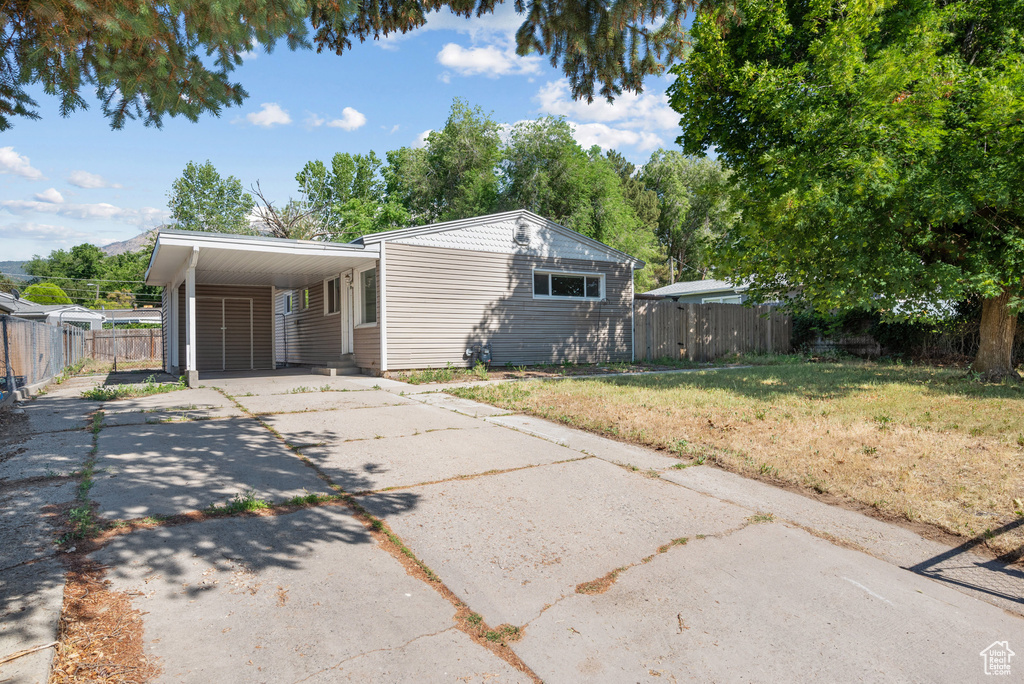 View of front facade with asphalt driveway and an attached carport