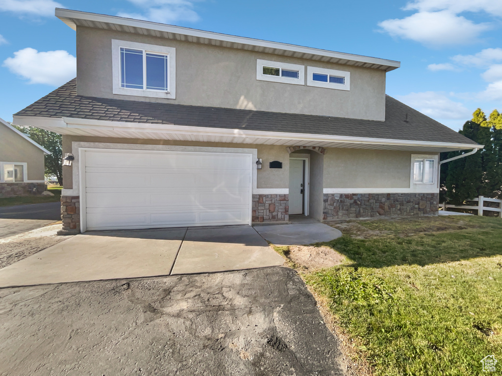 View of front of property featuring stone siding, concrete driveway, stucco siding, and an attached garage