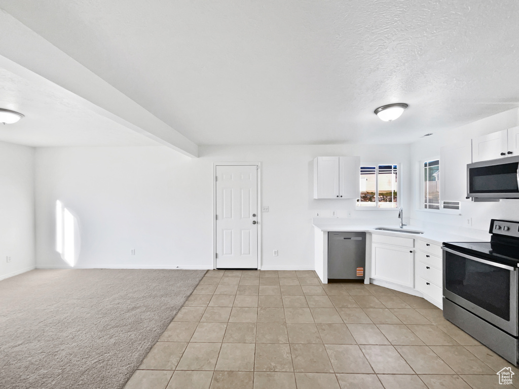 Kitchen with stainless steel appliances, white cabinets, and light countertops