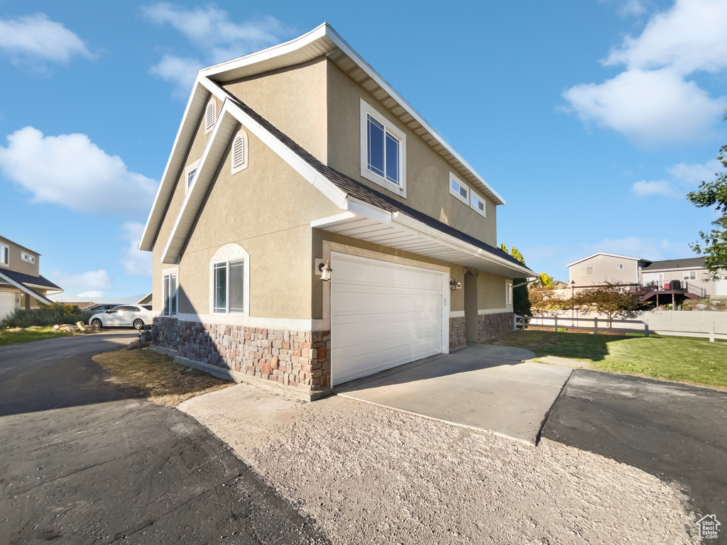 View of home\\\'s exterior featuring stone siding, stucco siding, concrete driveway, and a garage