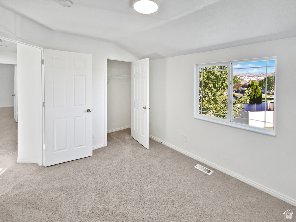 Unfurnished bedroom featuring carpet, lofted ceiling, and a closet