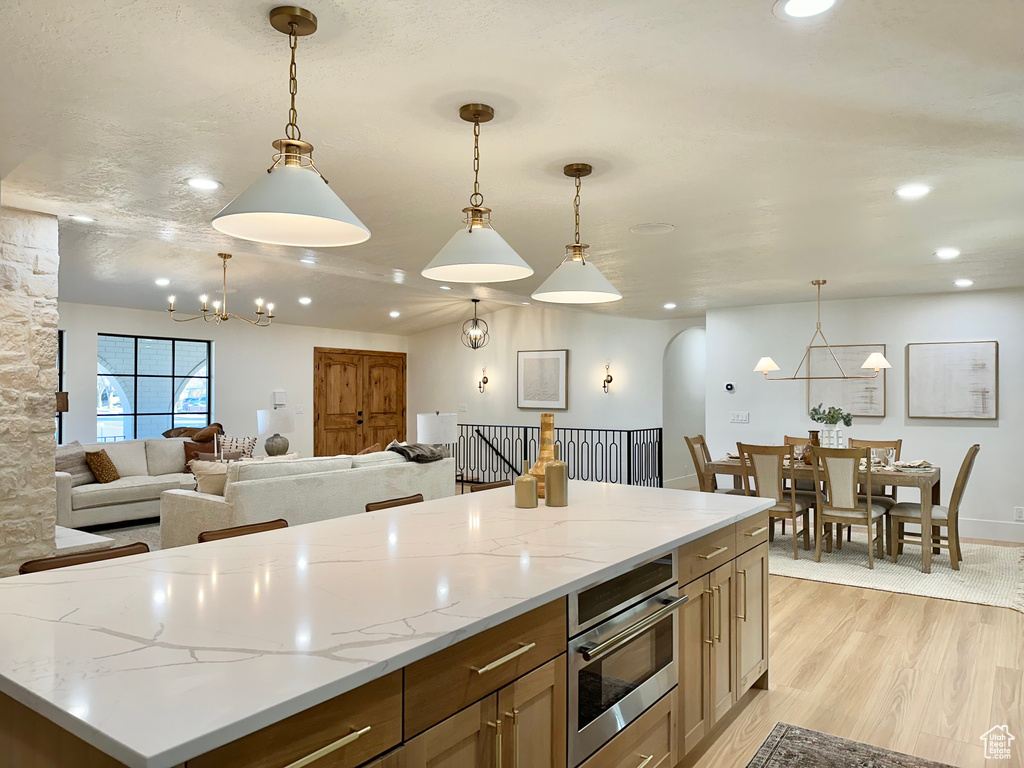 Kitchen featuring a chandelier, recessed lighting, light wood finished floors, open floor plan, and hanging light fixtures