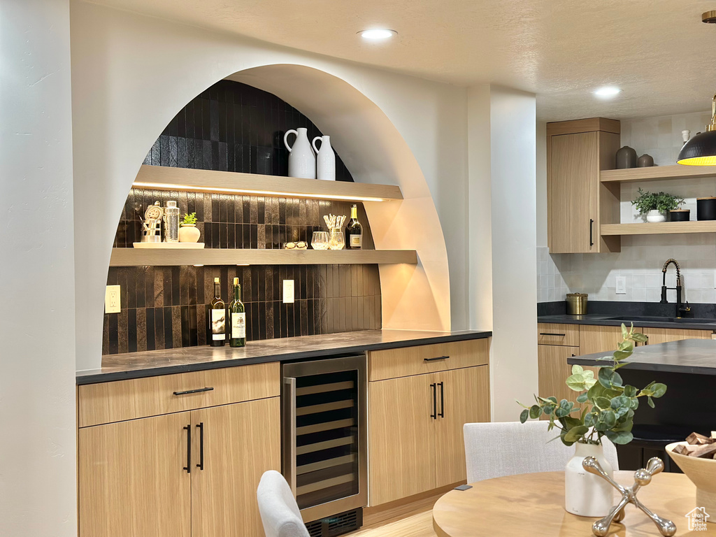 Indoor wet bar featuring wine cooler, backsplash, recessed lighting, and light wood finished floors