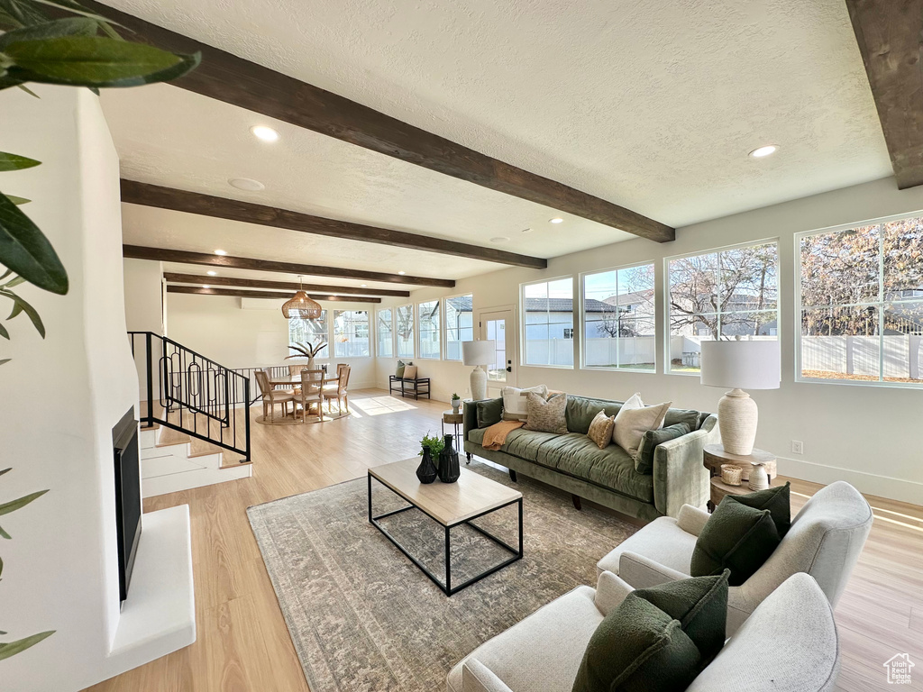 Living area featuring a textured ceiling, beamed ceiling, wood finished floors, recessed lighting, and stairs