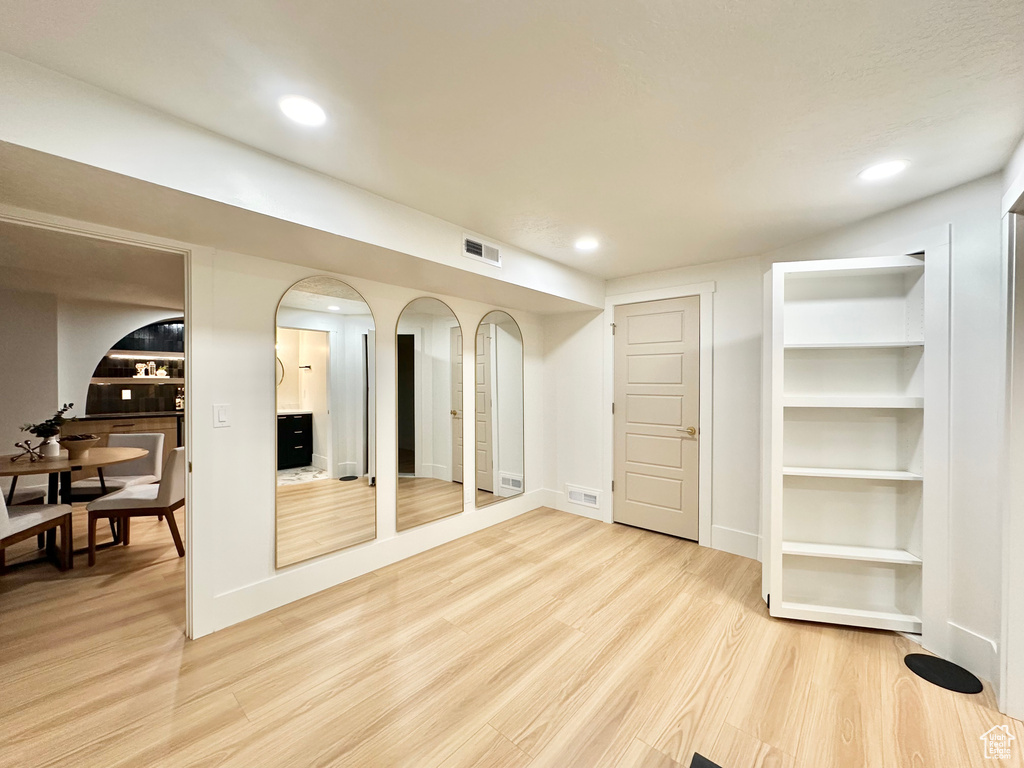 Below grade area with light wood finished floors, recessed lighting, and arched walkways